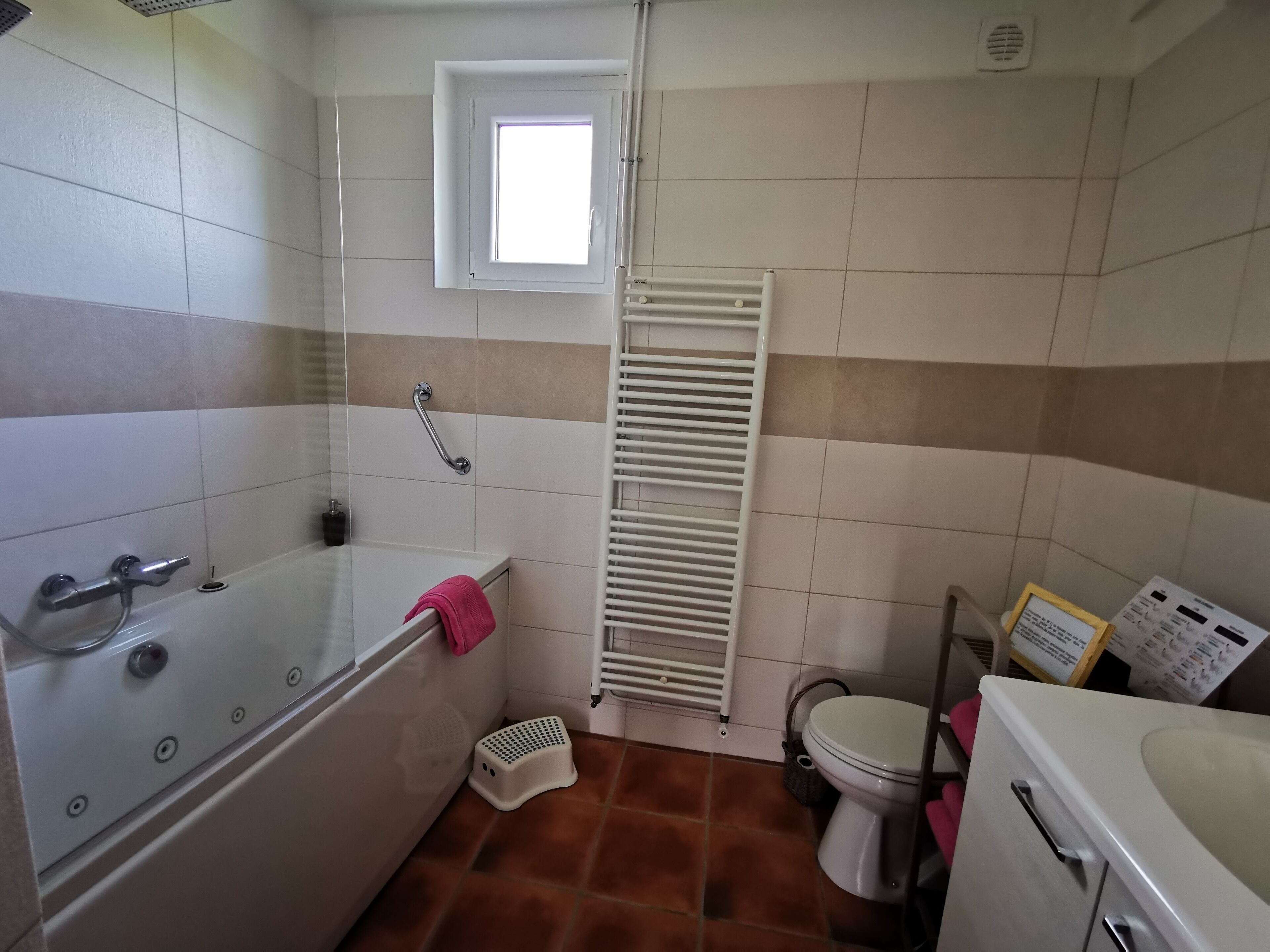 Une salle de bain avec une baignoire, des toilettes, une douche et une fenêtre.