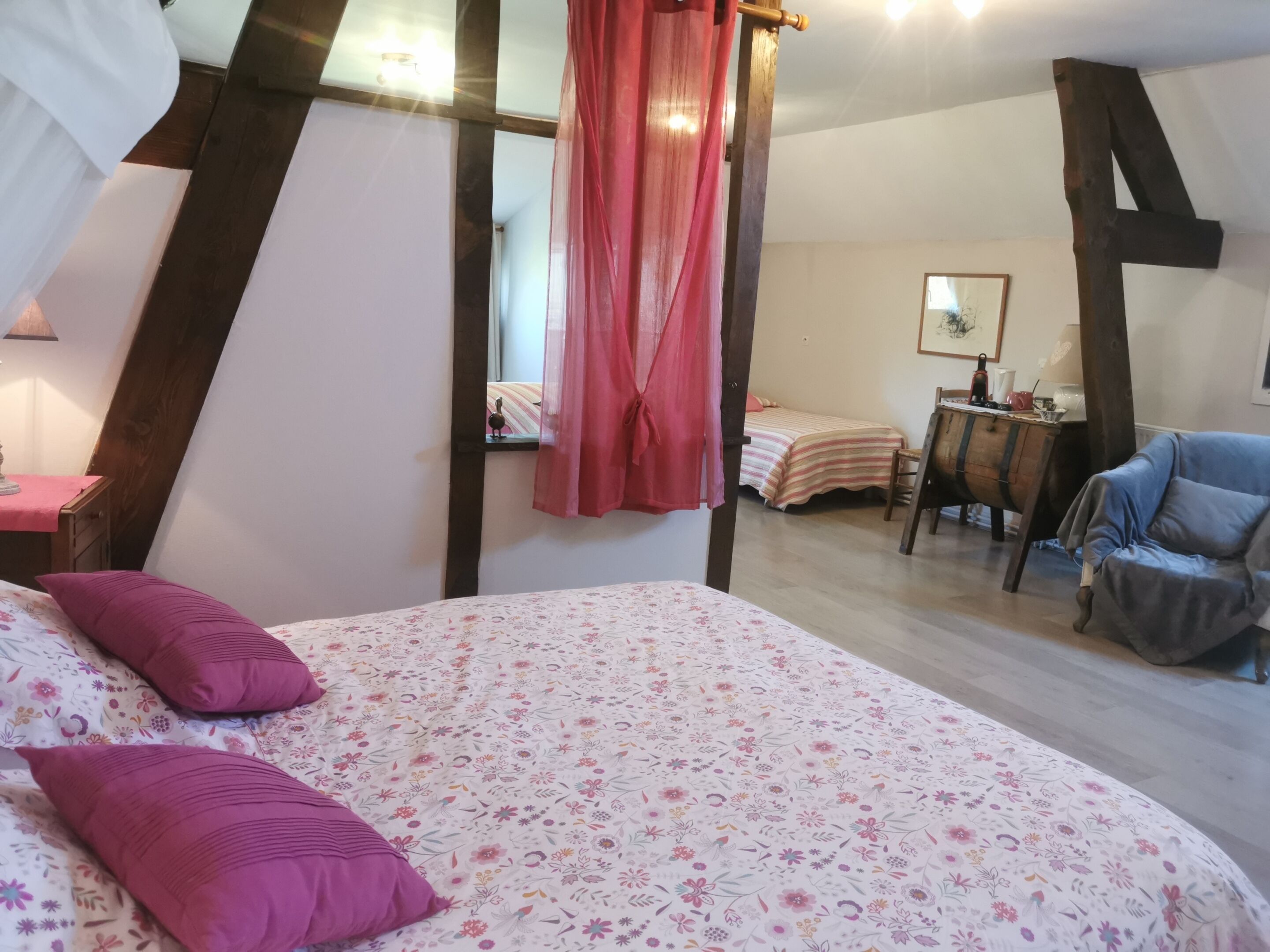 A bedroom with a bed, a chair, a desk, and a mirror.