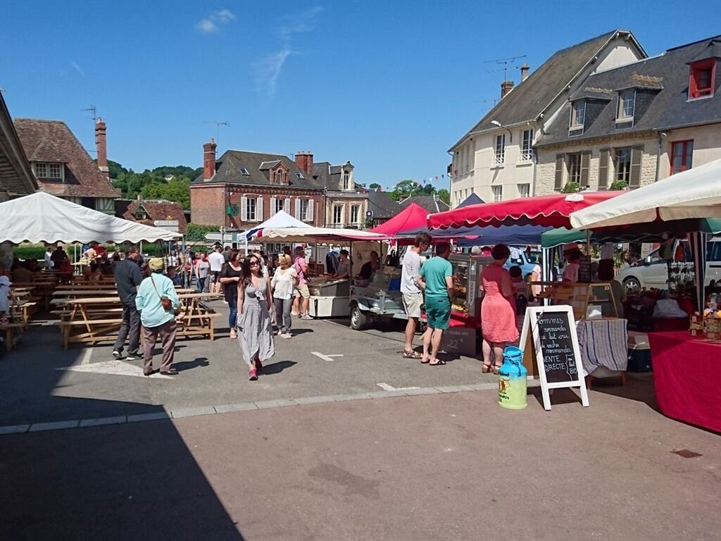 An outdoor market with people shopping and walking around.