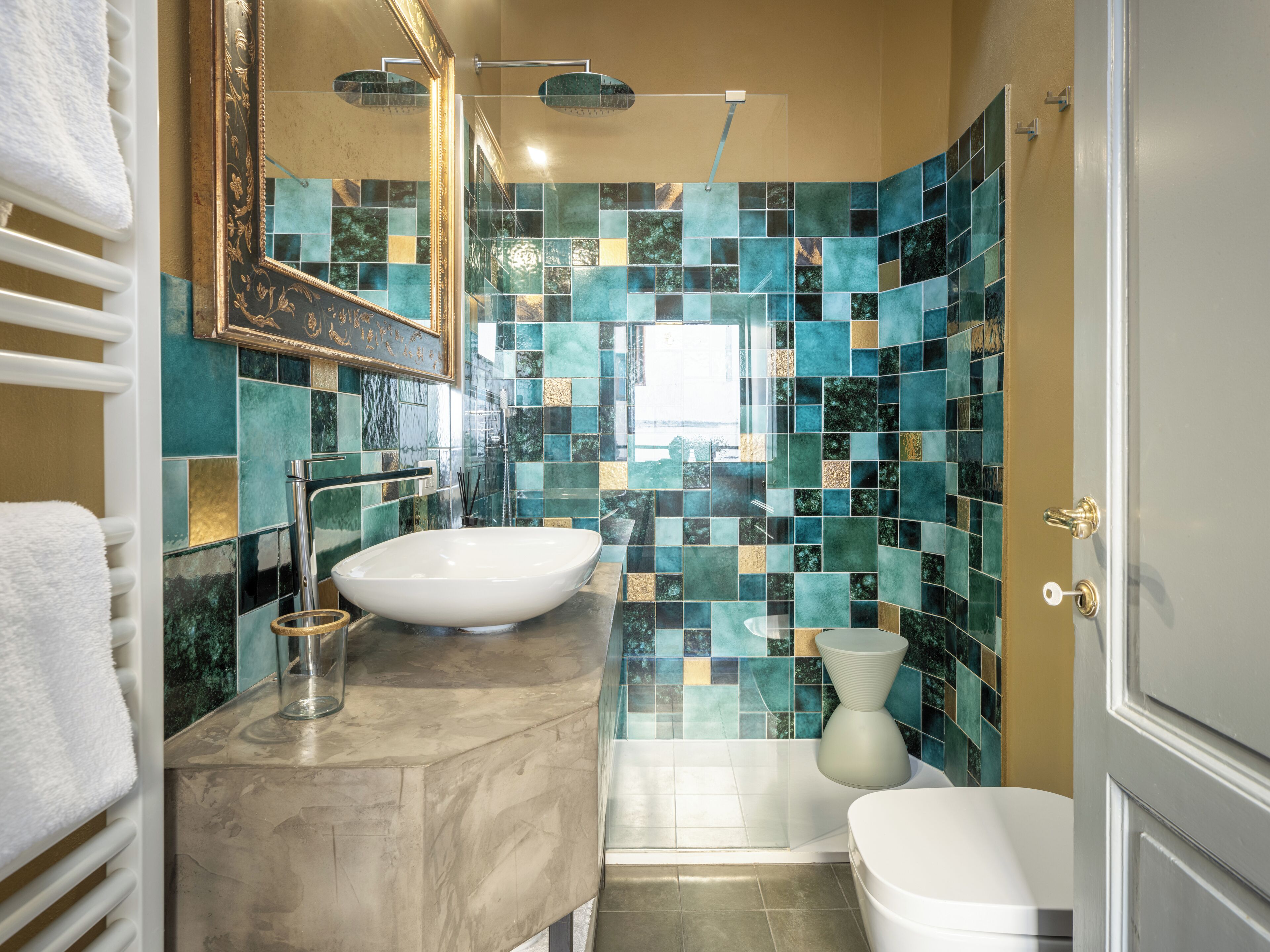 A bathroom with a white sink, a glass bowl, a modern shower, and a toilet.