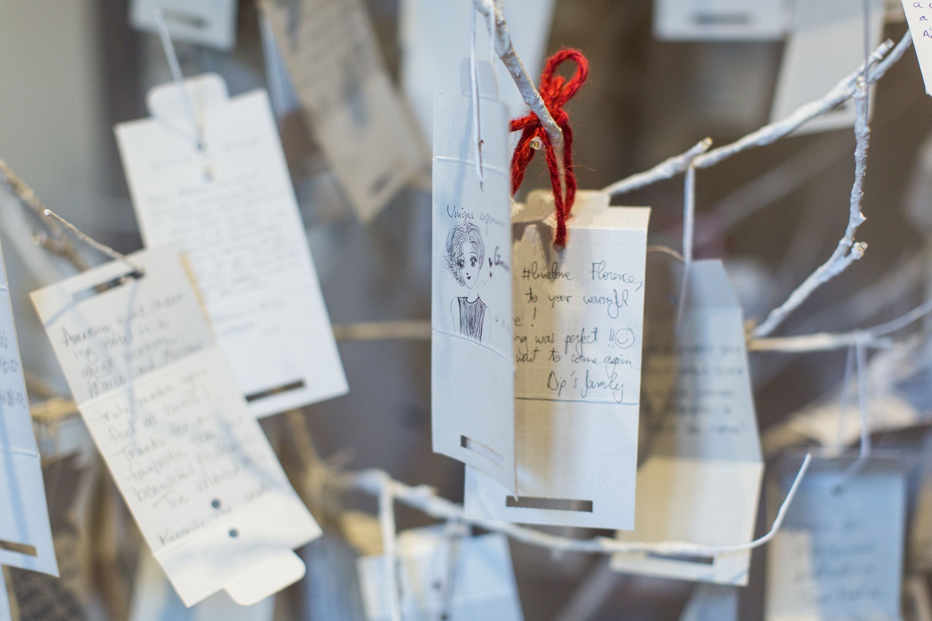 A display of handwritten notes attached to strings, likely for decoration or information purposes.