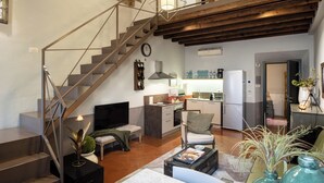 A spacious living area with a staircase leading to an upper level, a kitchen, and a seating area with a television. - Canto degli Scali (Florence)