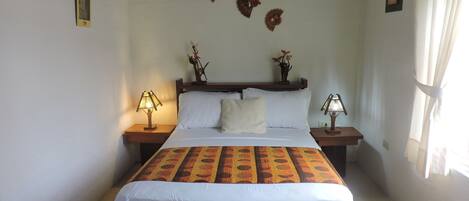 A neatly made bed with a patterned bedspread, two bedside lamps, and wall-mounted decorative items.