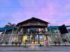 Un edificio de dos pisos con un balcón, un cartel que indica que es un albergue y una valla decorativa.