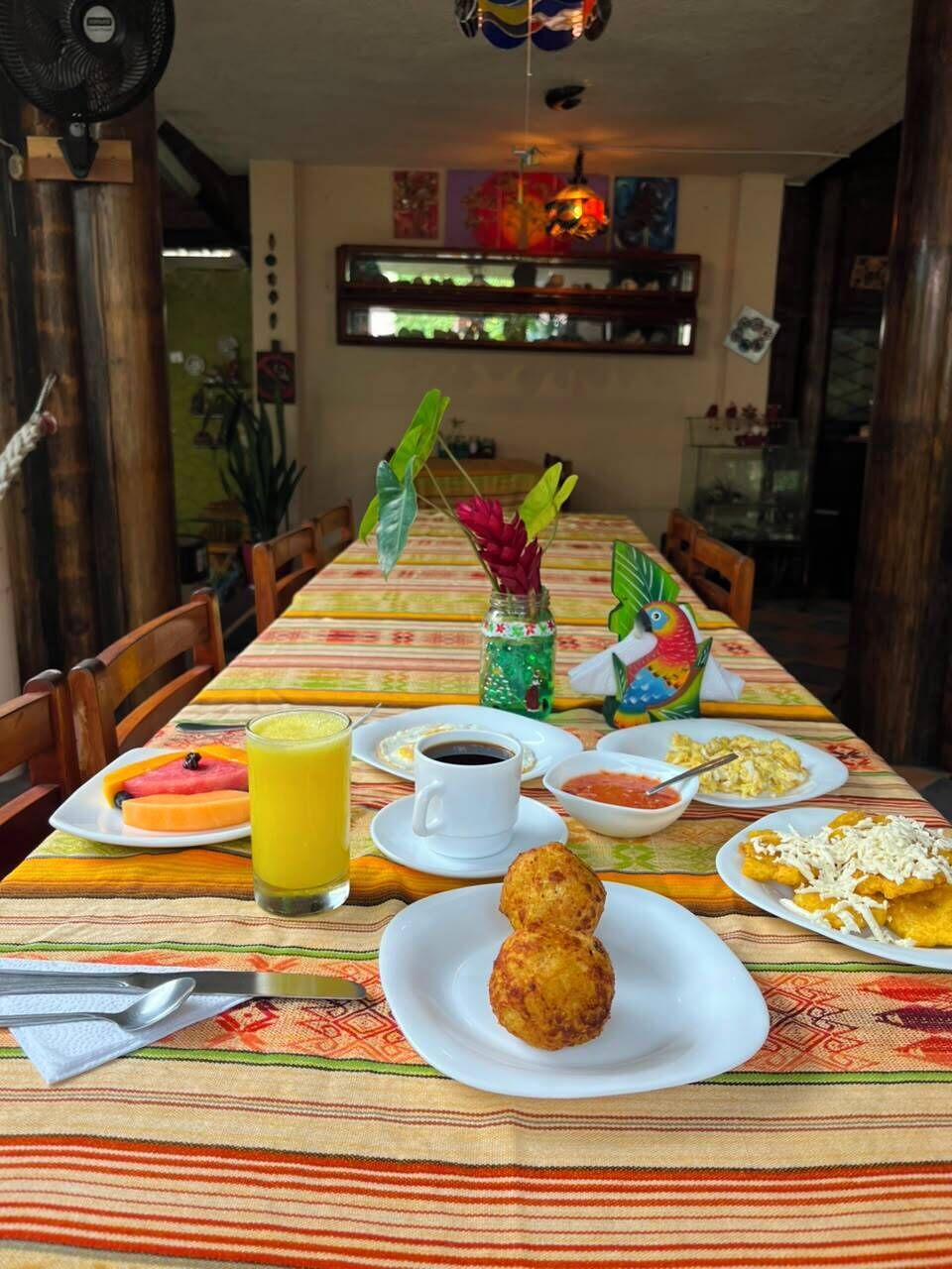 Una mesa de comedor con alimentos para el desayuno, incluyendo platos de comida, una taza de café y un vaso de jugo.