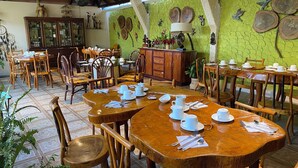 Ein Restaurant mit Holztischen und -stühlen, grünen, strukturierten Wänden und dekorativen Wandbildern.