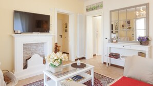 A living room with a fireplace, a television, a coffee table, and a large mirror. - Nina Guest House (Castegnero)