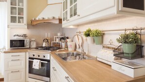 A modern kitchen with white cabinets, a wooden countertop, a stainless steel sink, and a tea station. - Nina Guest House (Castegnero)