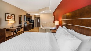 A hotel room with a large bed, a desk, a chair, a desk lamp, a TV, a coffee maker, a microwave, a sink, and a bathtub. - Best Western Plus Kindersley Hotel (Kindersley)