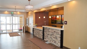 A reception area with a stone counter, pendant lighting, and a painting on the wall. - Best Western Plus Kindersley Hotel (Kindersley)