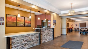 A hotel reception area with a stone counter, multiple pendant lights, and framed artwork on the wall. - Best Western Plus Kindersley Hotel (Kindersley)