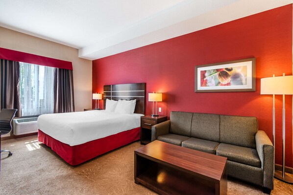 Una habitación de hotel con cama, sofá, mesa de centro, escritorio y silla.