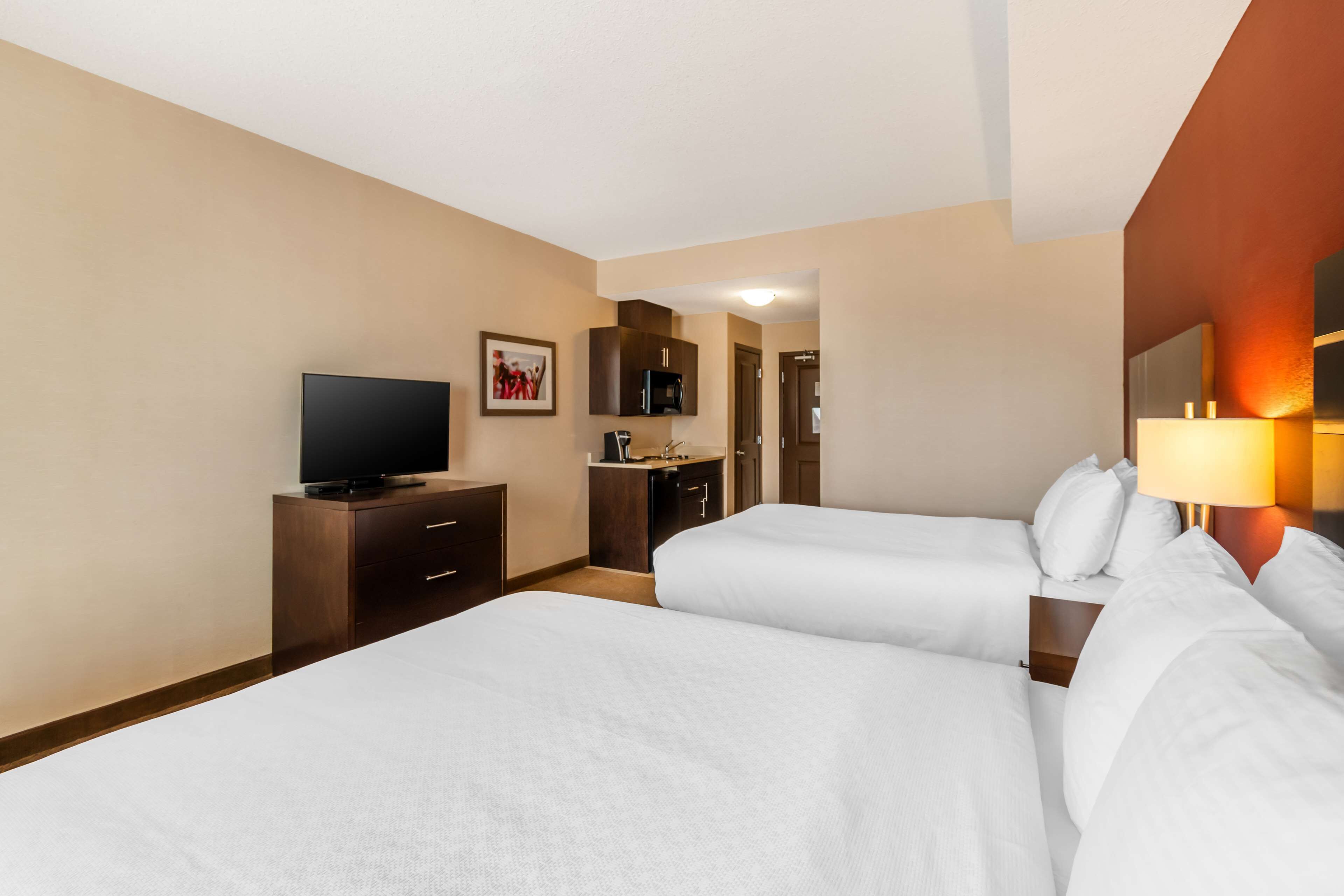 Habitación de hotel con dos camas, televisión, escritorio y baño.