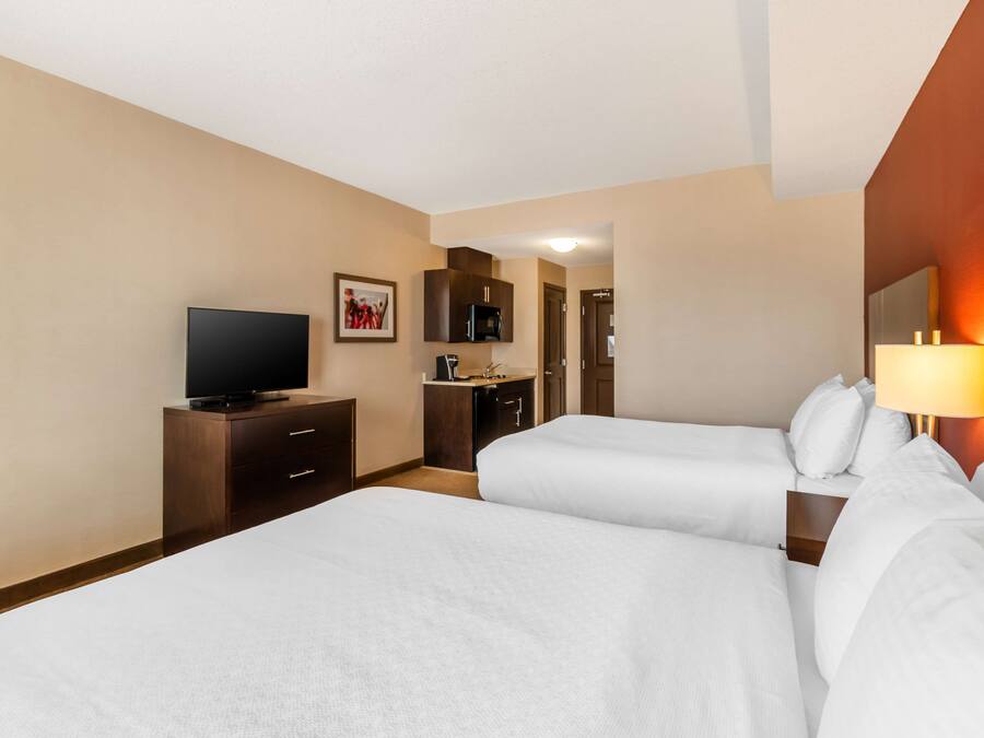 Habitación de hotel con dos camas, televisión, escritorio y baño.