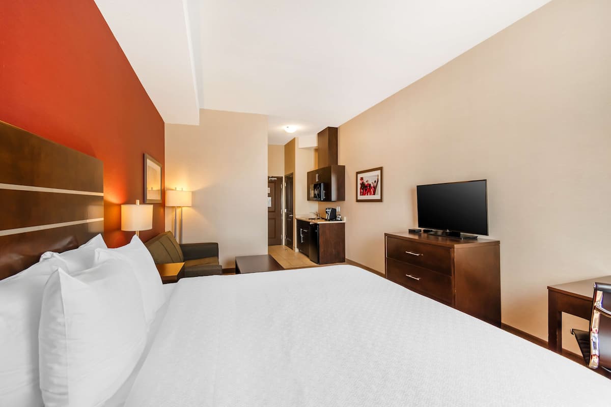 Een hotelkamer met een groot bed, een bureau, een televisie en een badkamer in de achtergrond.