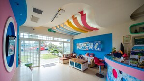 A brightly colored reception area with a large window, a seating area, and a counter with various items. - Love Jane B&B (Hengchun)