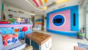 A vibrant room with a colorful ceiling, a wooden table, and a seating area with a patterned cushion. - Love Jane B&B (Hengchun)