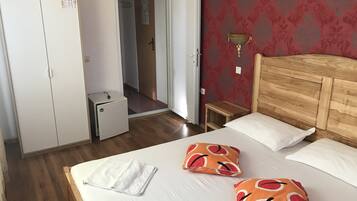 Een hotelkamer met een houten bed, witte kussens, een klein nachtkastje en een kledingkast.