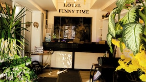 A reception area with a sign reading "RECEPTION HOTEL FUNNY TIME," a reception desk, a bicycle, and various plants. - Hotel Funnytime (Bucharest)