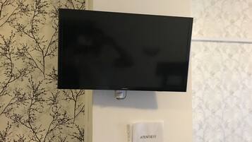 Un téléviseur à écran plat fixé au mur, avec un papier peint à motifs et un panneau avec du texte.