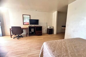 A hotel room with a bed, a desk with a computer, a chair, a television, and a microwave. - Executive Inn & Suites Provo Near University (Provo)