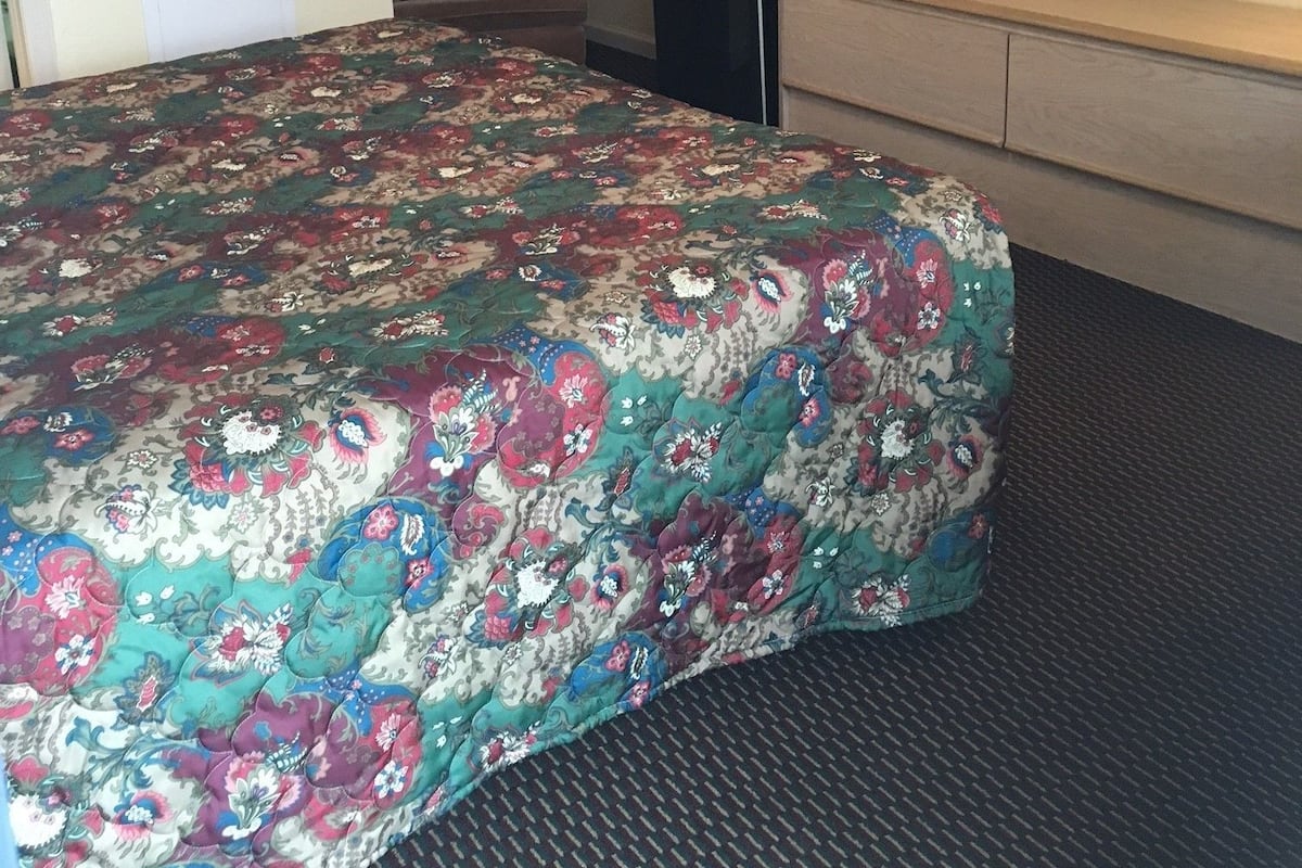 Une chambre d’hôtel équipée d’un lit, d’un téléviseur fixé au mur, d’un four à micro-ondes et d’un réfrigérateur.
