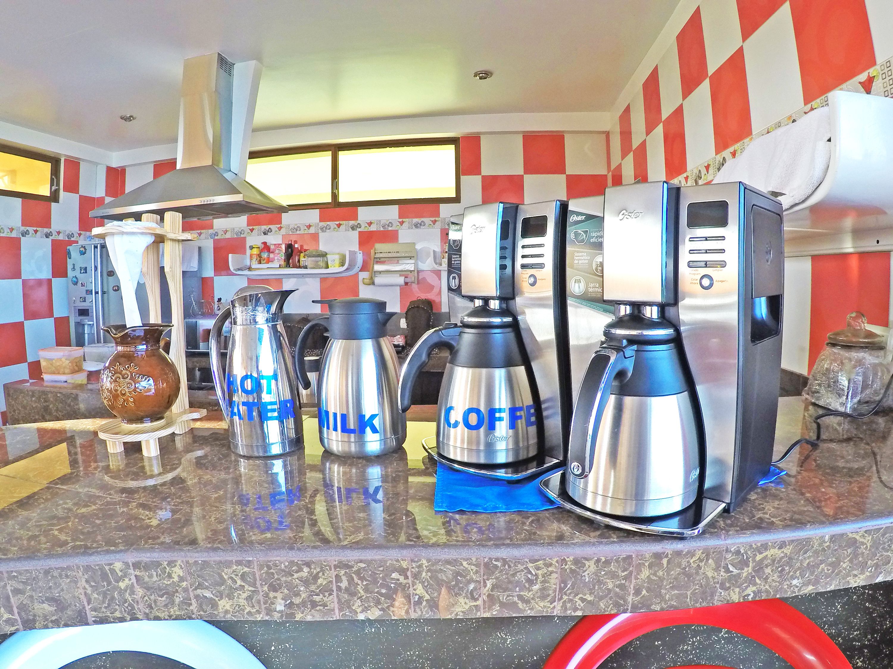 A kitchen with coffee makers labeled "HOT WATER," "MILK," and "COFFEE," and a coffee machine with a digital display.