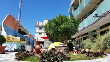 A courtyard with potted plants, a mural, and a building with balconies.