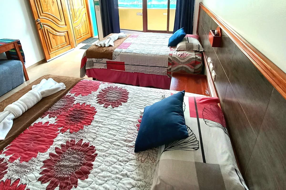 Ein Hotelzimmer mit zwei Betten, einem Balkon mit Blick, Holzbalken an der Decke und einem großen Spiegel an der Wand.