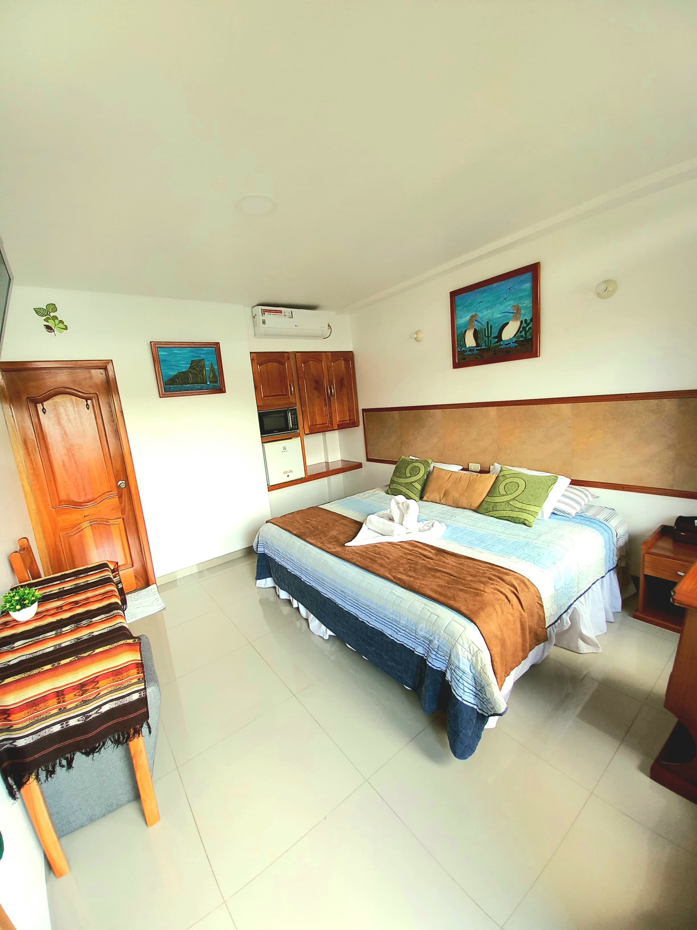A bedroom with a bed, a wooden headboard, a small table with a plant, and a door.