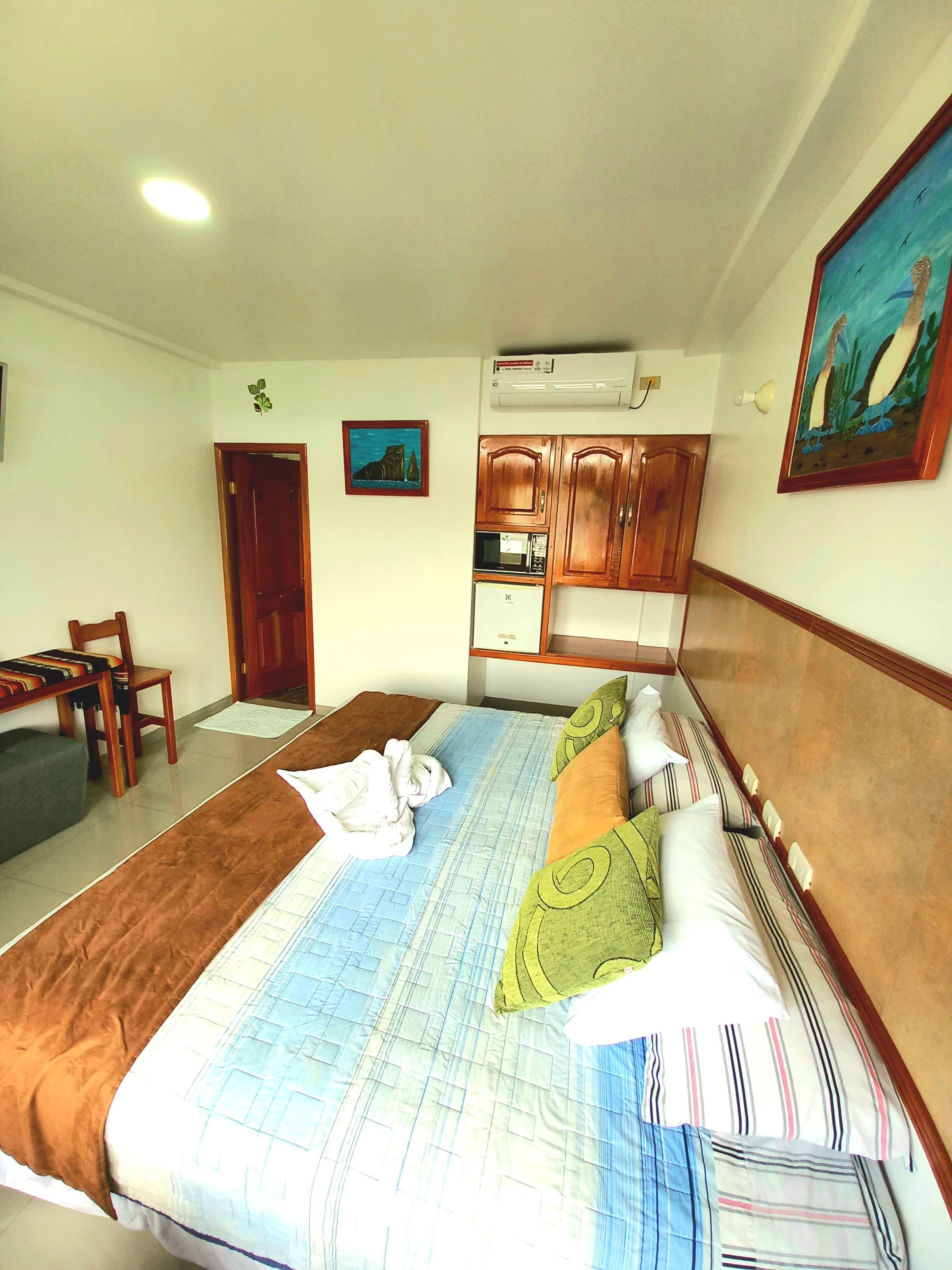 A hotel room with a bed, a dining table, and a kitchenette.