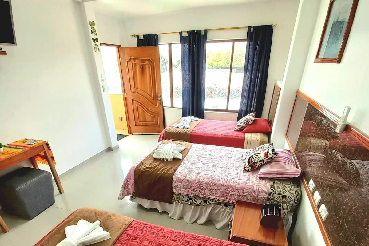 Ein Hotelzimmer mit zwei Betten, einem Schreibtisch und einem Fenster mit Vorhängen.