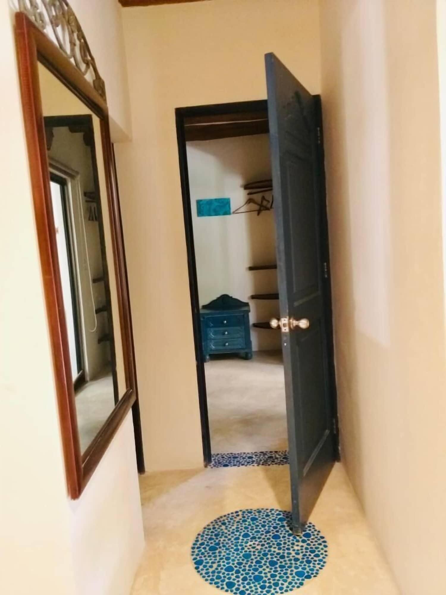 A hallway with a wooden door, a blue mat, and a dresser in the background.