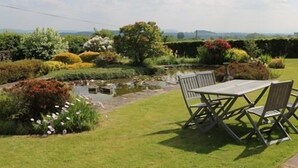 A garden with a pond, a table, and chairs. - Mortimer Trail B & B (Leominster)