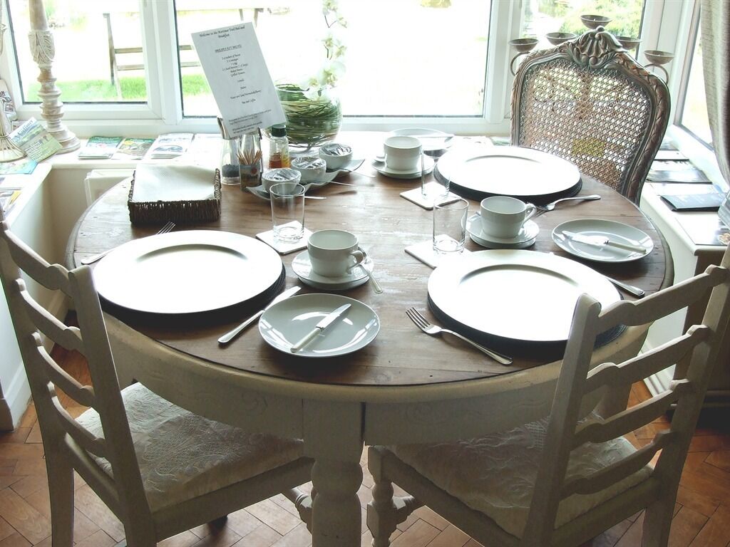 A dining table set for four with white plates, cutlery, and glasses.