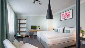 A modern hotel room with a bed, a desk, a chair, and a sofa. - Hotel Rotkreuzplatz (Munich)