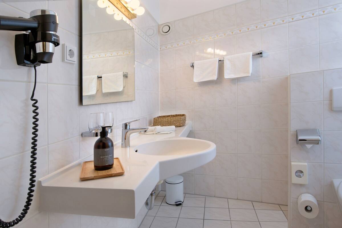 A modern bathroom with a large sink, mirror, and hair dryer.