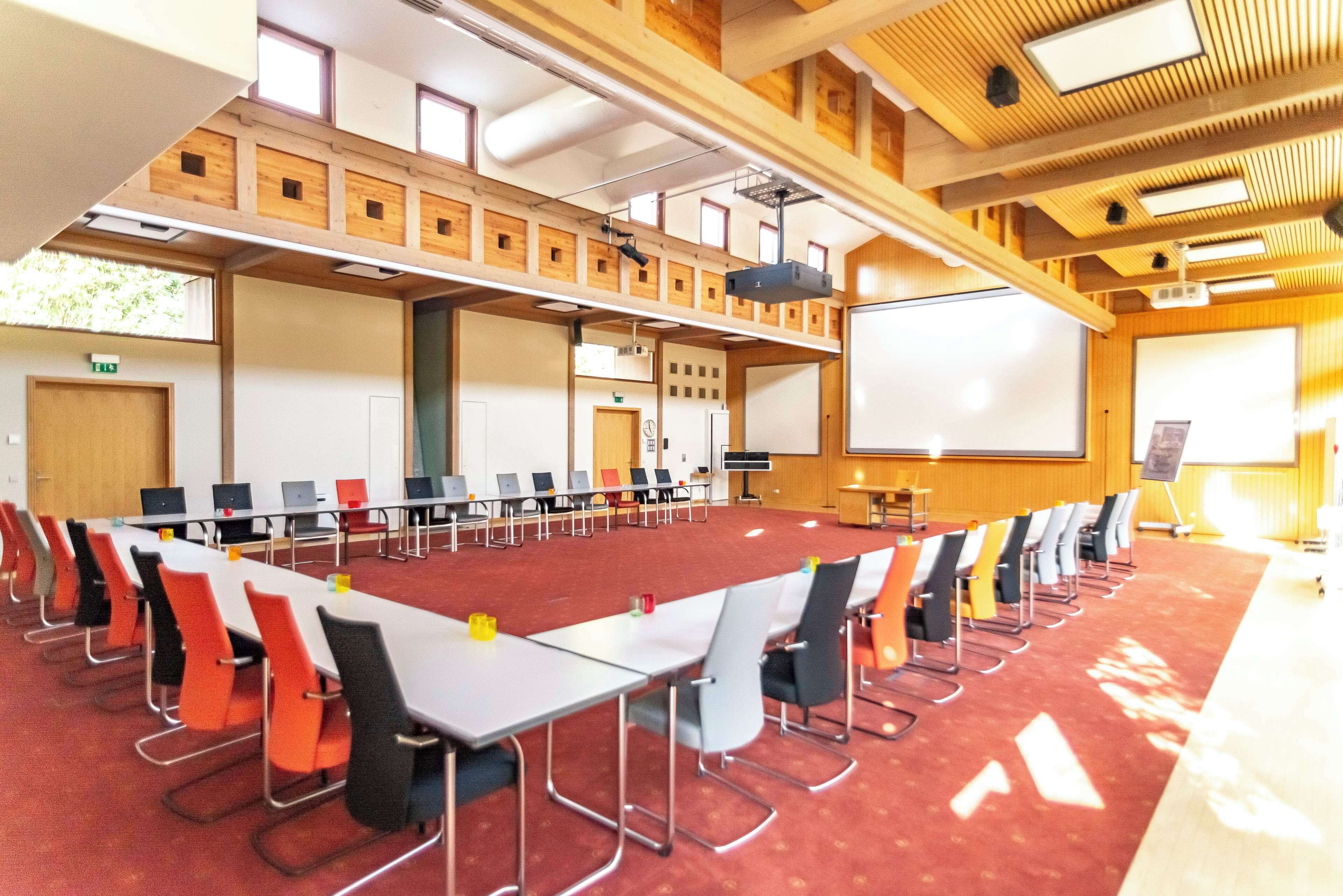 A conference room with a long table, chairs, a projector screen, and a whiteboard.