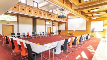 A conference room with a long table, chairs, a projector screen, and a whiteboard.