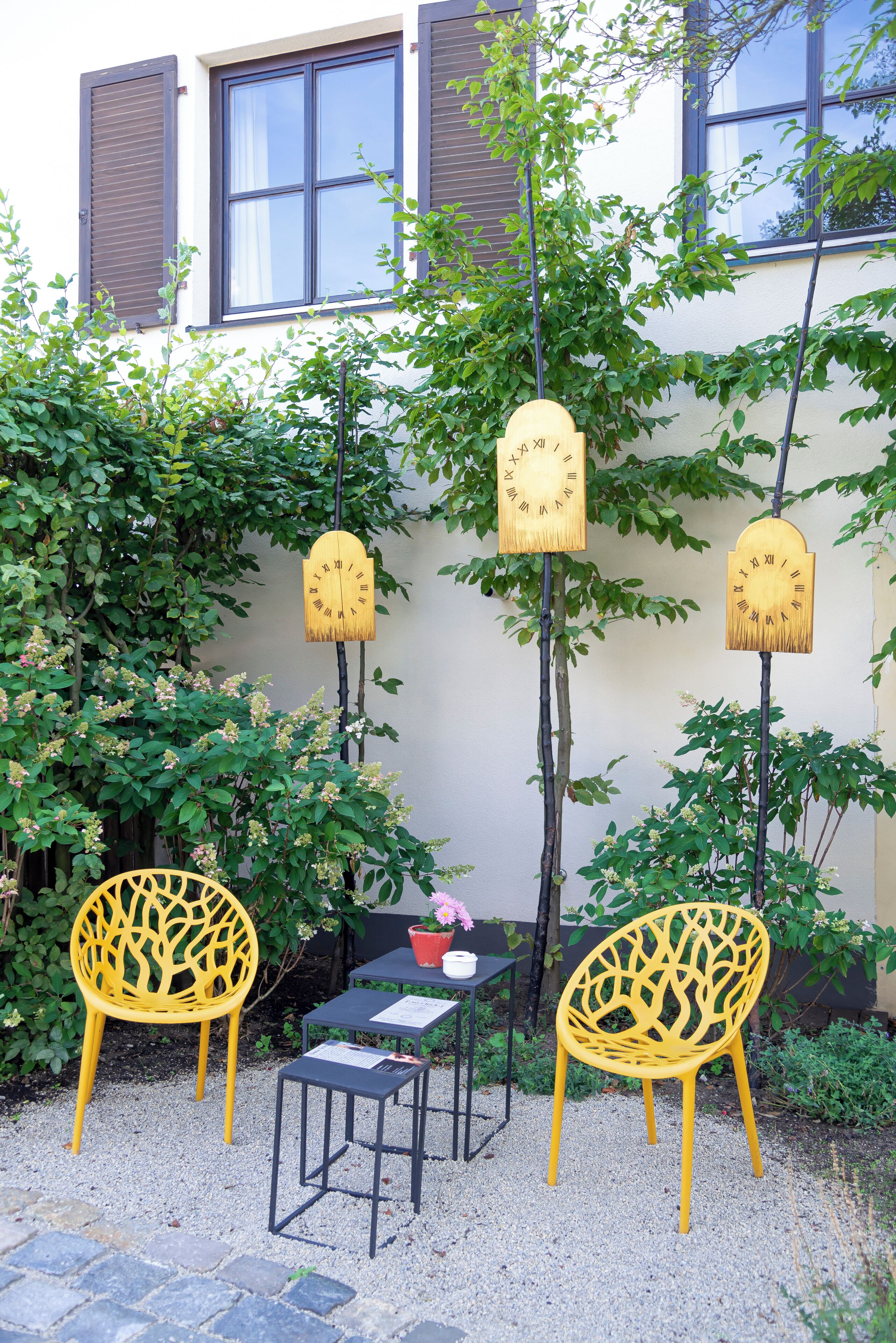 Un patio con dos sillas amarillas, una mesa pequeña y una planta en maceta.