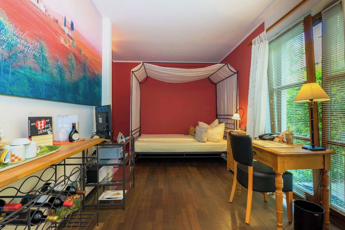 Una habitación de hotel pequeña con cama, escritorio, silla, ordenador y televisor.