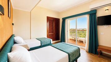 Habitación de hotel con dos camas, balcón con vistas, televisor y aire acondicionado.