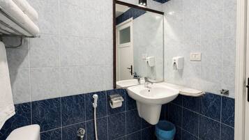 Un baño con un lavamanos blanco, un espejo, un inodoro y azulejos azules.