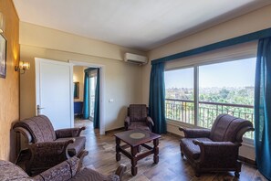Een ruime woonkamer met een balkon, uitzicht over de stad en een deur naar een andere kamer.