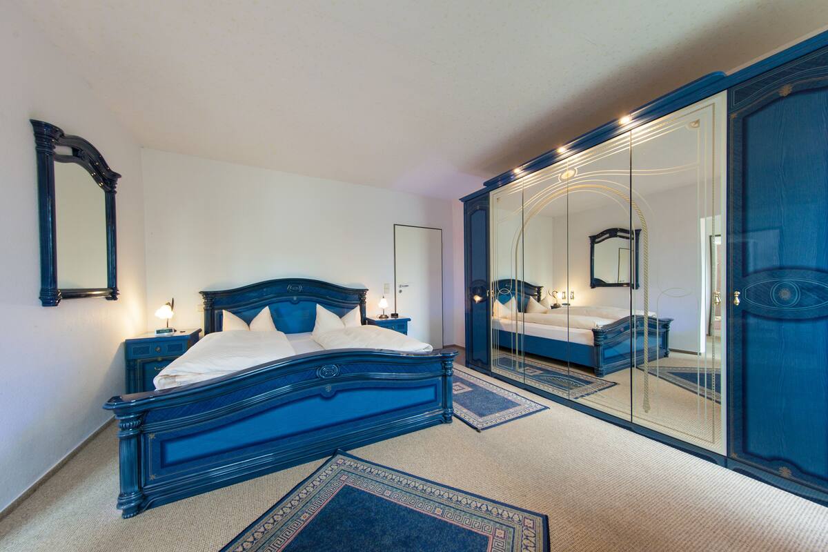 A bedroom with a large bed, a wardrobe, and a mirror.