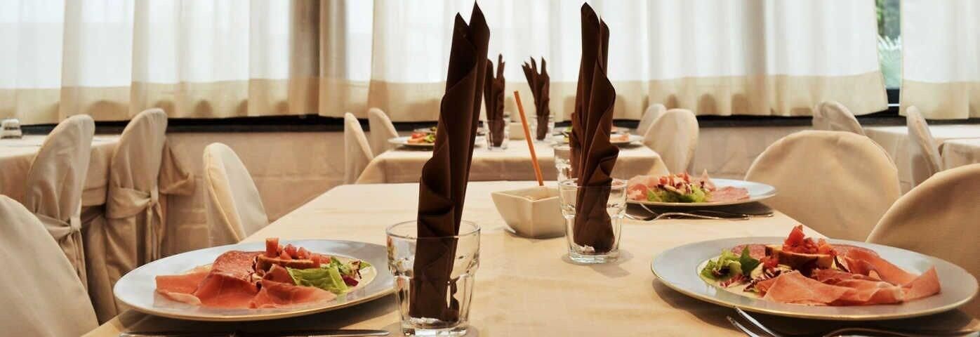 A dining area with tables set for meals, each with neatly folded napkins and plates of food.