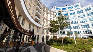 A modern hotel with multiple floors, balconies, and a central courtyard with greenery. - Hôtel de Berny (Antony)