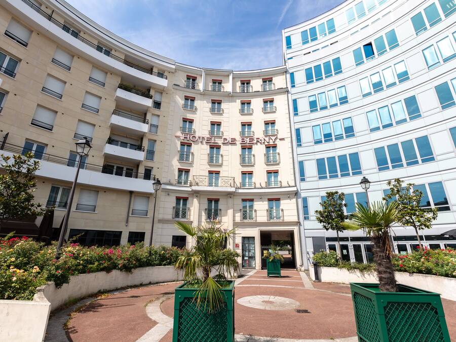 Een hotel met meerdere verdiepingen, balkons, een centrale ingang en omliggend groen.