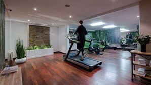 A spacious room with a wooden floor, a treadmill, and exercise equipment. - Hôtel de Berny (Antony)