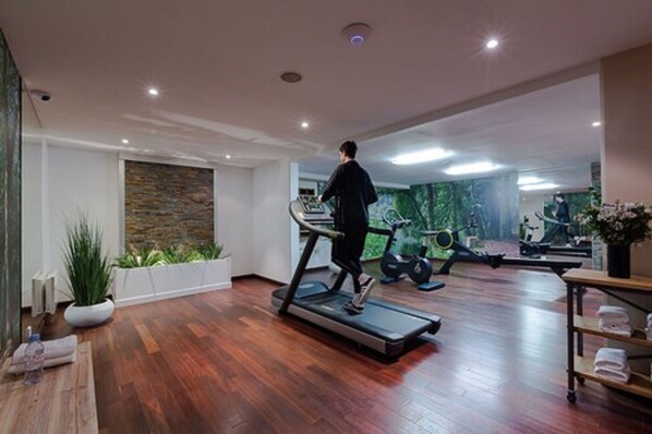 A spacious room with a wooden floor, a treadmill, and exercise equipment.
